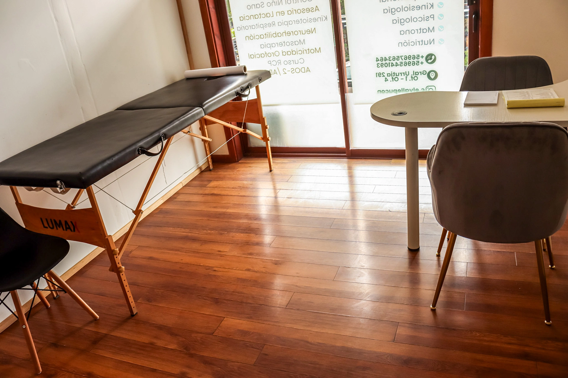 Sala amplia de kinesiología con dos camillas profesionales, piso de madera y luz natural