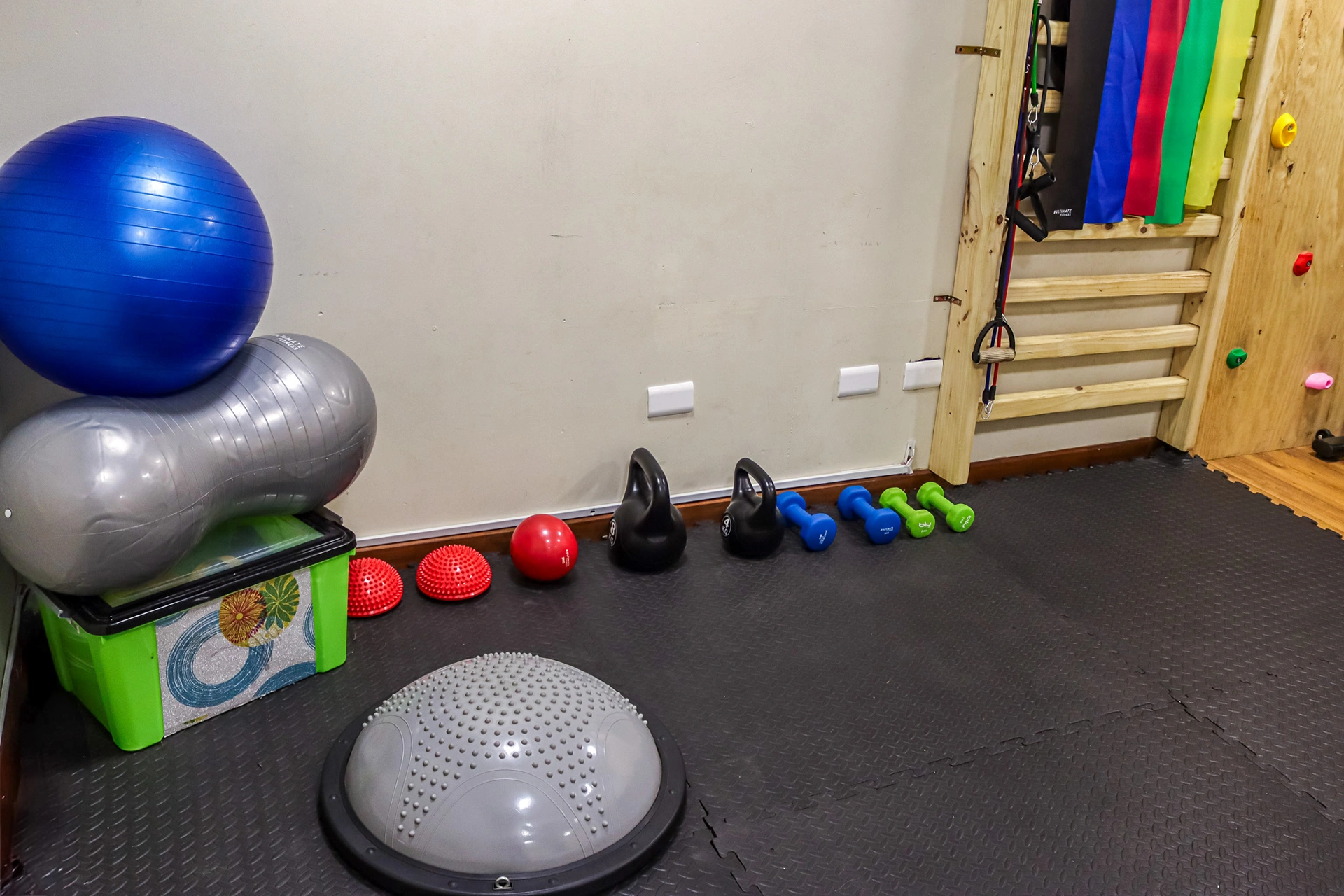 Sala de integración sensorial con pelotas de colores, balones medicinales, scooter y banco de pesas